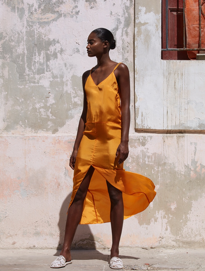 Melodie Monrose poses in orange slip dress with split front