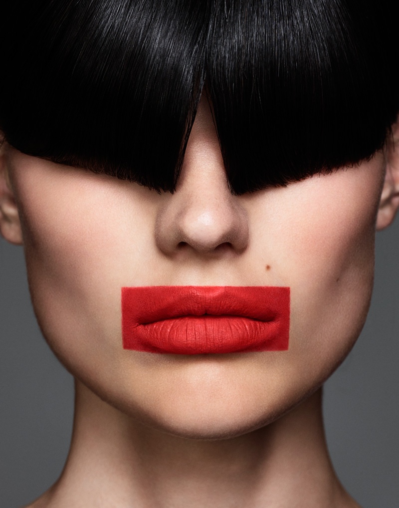The model wears long fringe and red lipstick