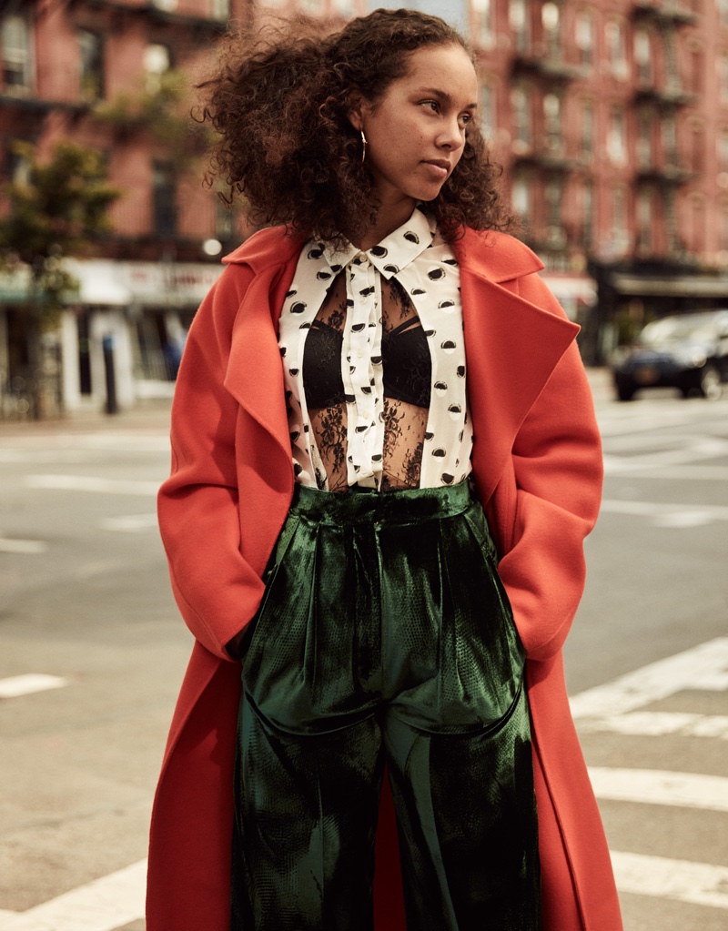 Alicia Keys poses in red coat, sheer top and green pants