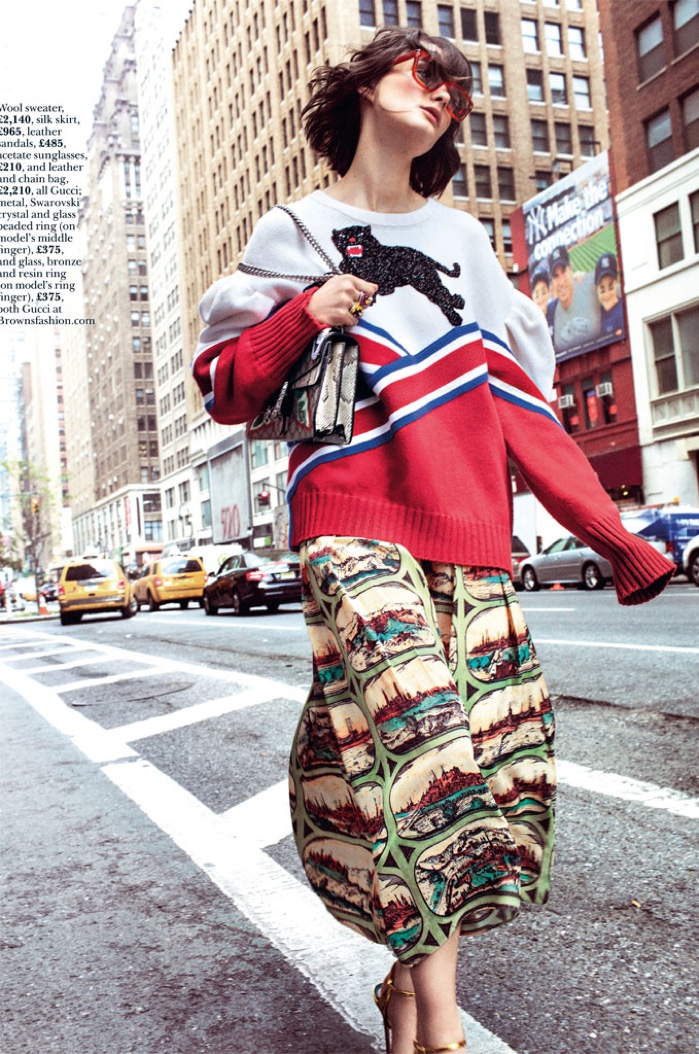 The model embraces a whimsical look in a Gucci sweater, skirt, shoes, bags and shades