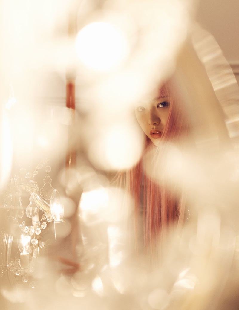 The pink haired model peers through glowing lights