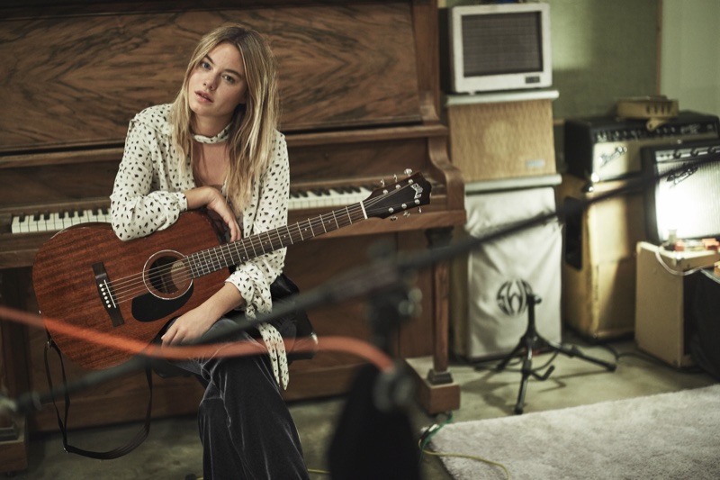 Posing with a guitar, Camille Rowe wears bow-printed blouse and velvet pants