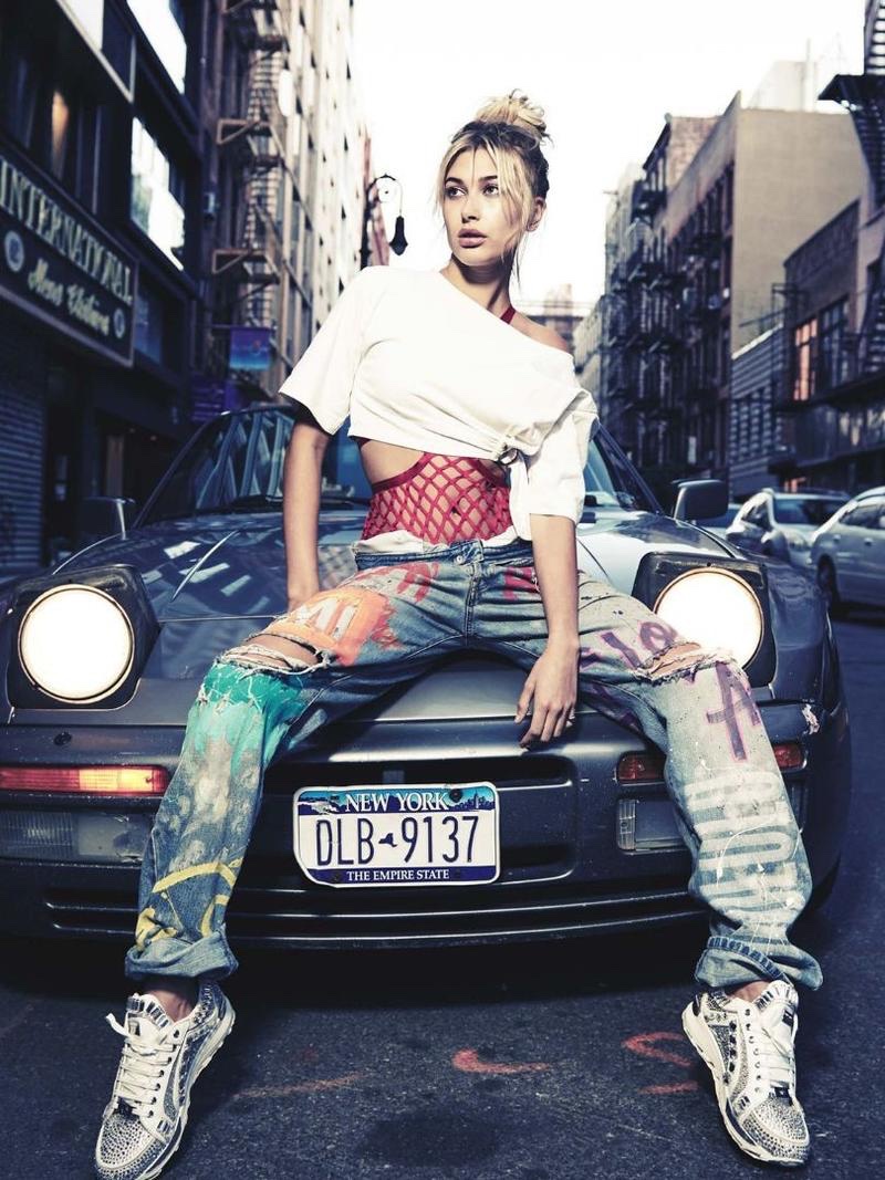 Posing on a car, Hailey Baldwin models cropped top with distressed denim