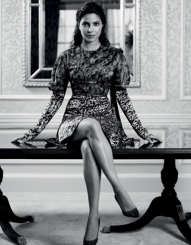 Priyanka Chopra poses on a bench wearing embroidered dress and long sleeve shirt