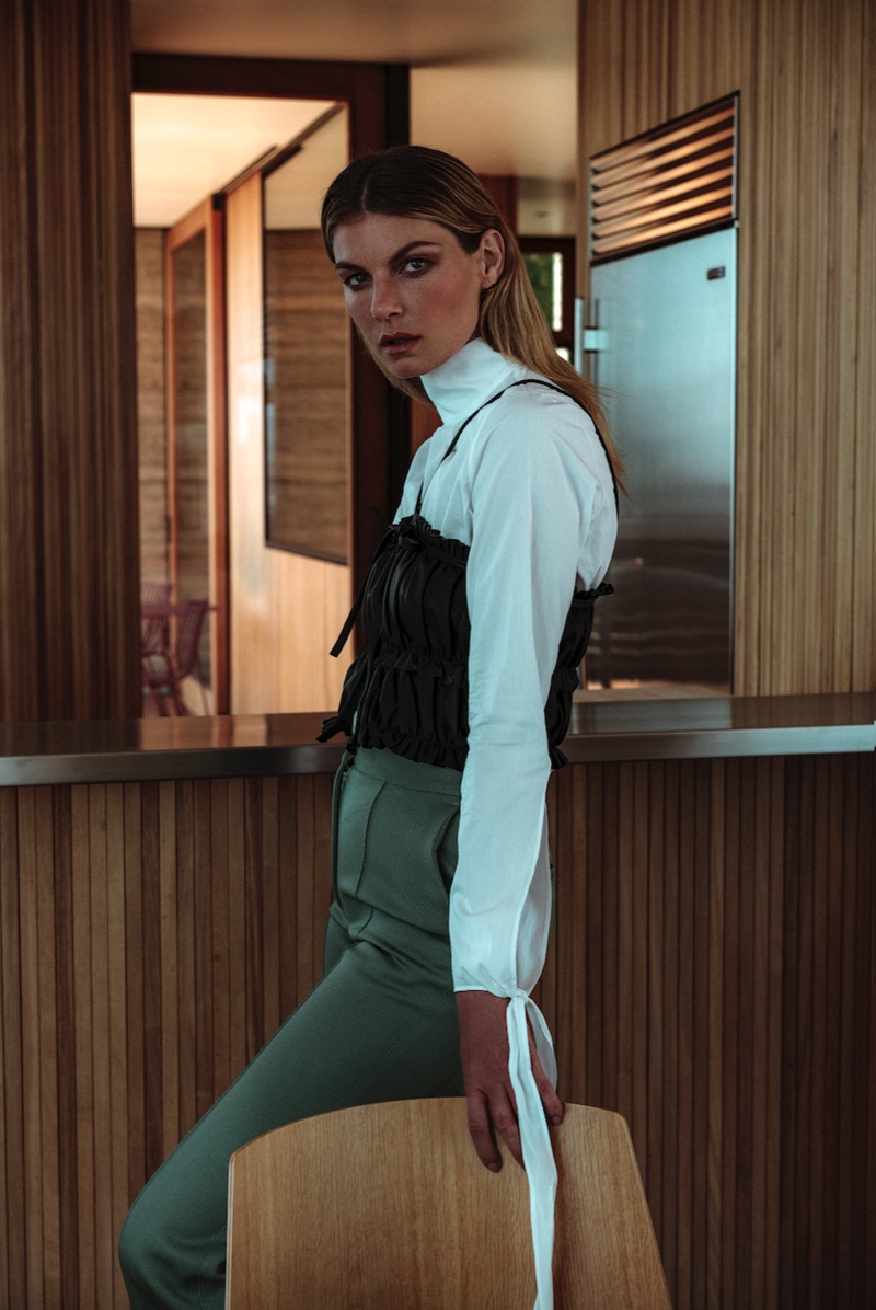 Model Angela Lindvall poses in long-sleeve blouse with sheer camisole top and high-waisted pants