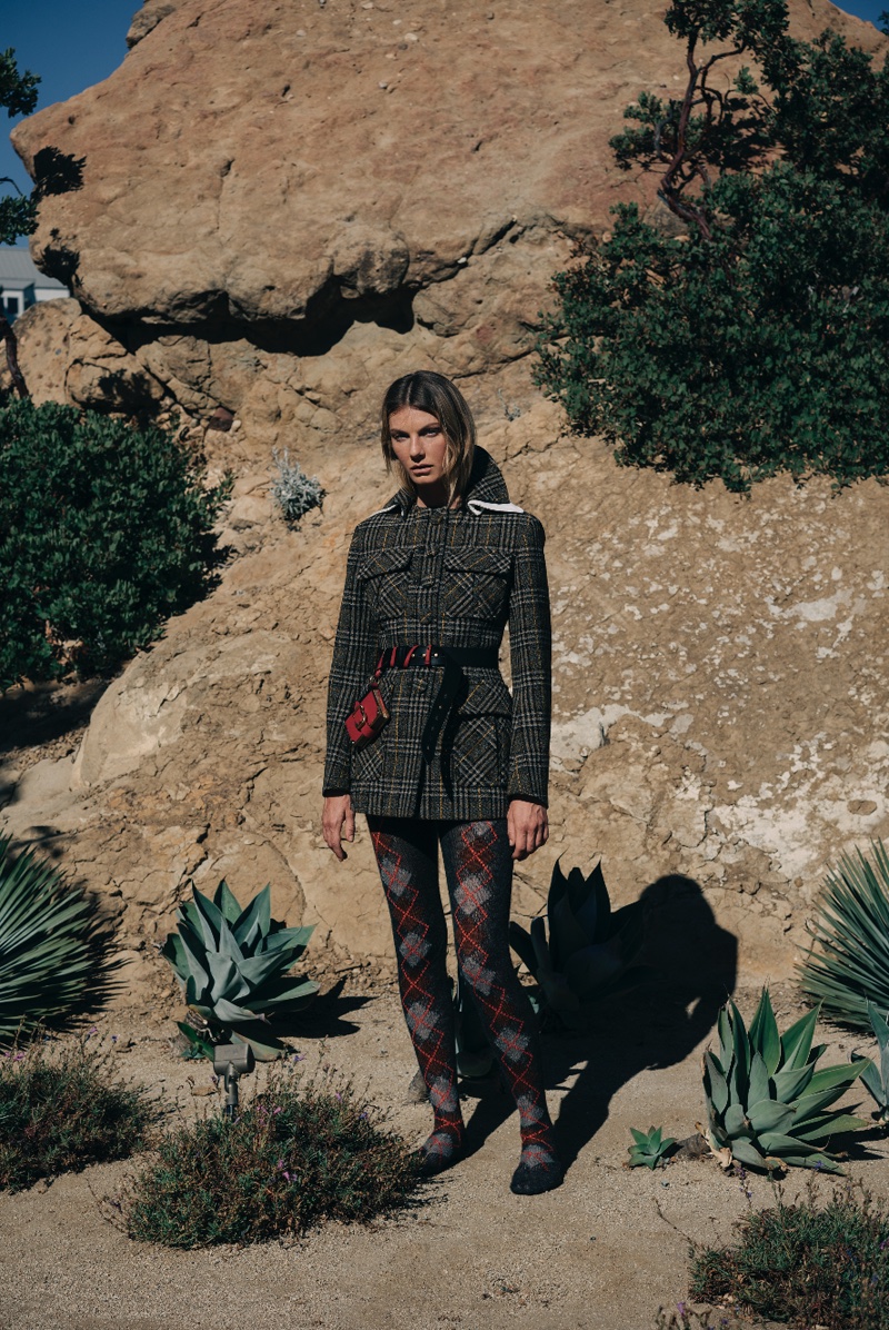 The model poses in Prada checkered jacket and argyle leggings