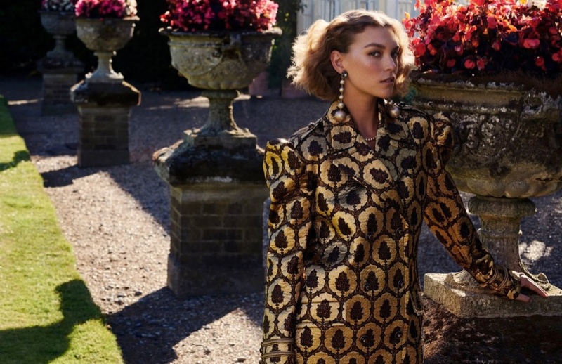 Wearing puffed up sleeves, the model poses in a gold brocade coat from Gucci