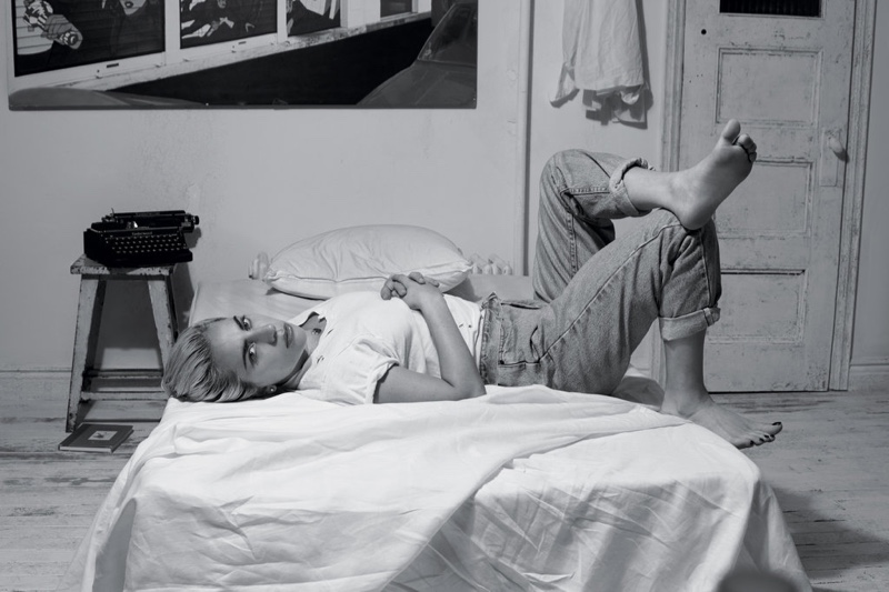 Lounging on a bed, Lady Gaga wears wears a white t-shirt and jeans