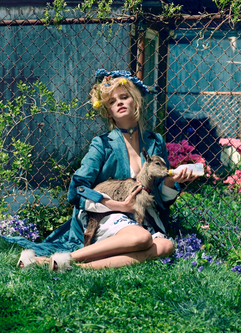 Model Lara Stone poses in the grass wearing Miu Miu denim jacket and embellished dress