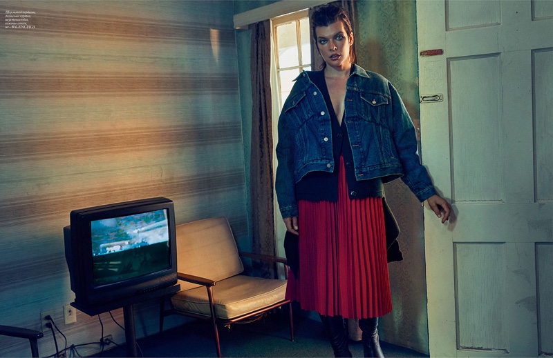 Milla Jovovich layers up in Balenciaga denim jacket, sweater, pleated skirt and boots
