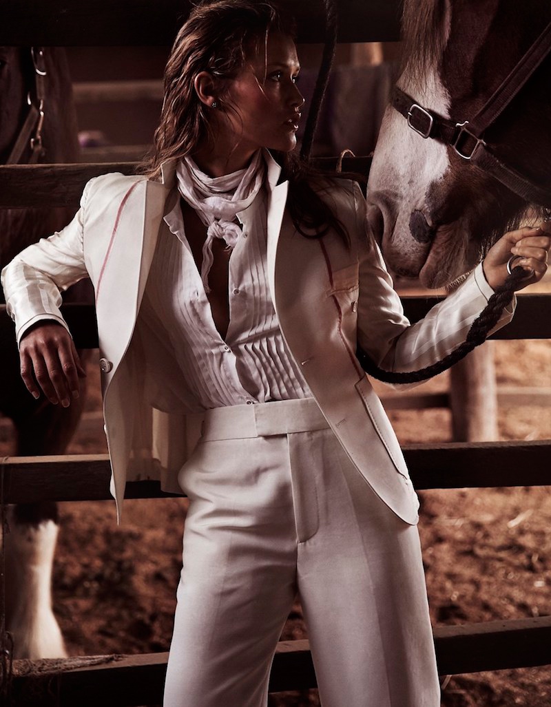Posing next to a horse, the model suits up in Bally jacket and pants with Karen Walker pleated shirt