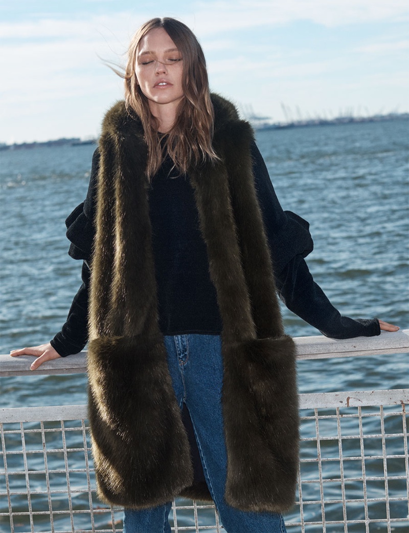 Posing in front of the sea, Sasha Pivovarova models Zara long faux fur vest with hood and long jeans