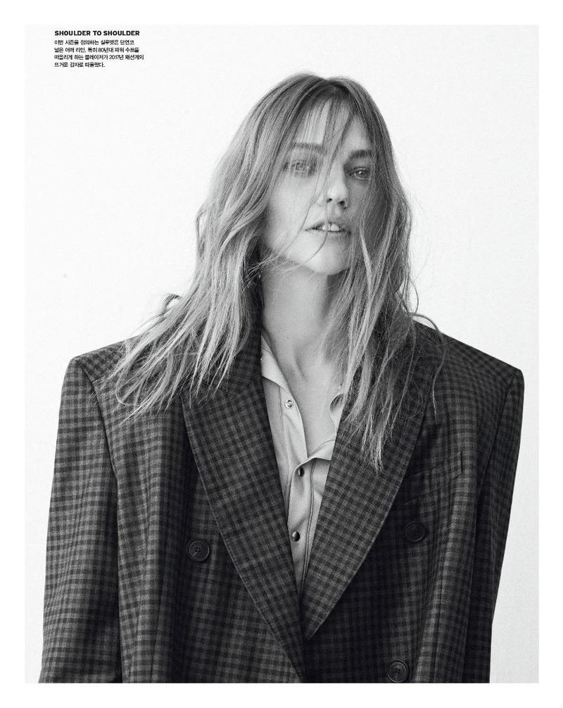 Photographed in black and white, Sasha Pivovarova wears Balenciaga plaid coat and button-up shirt