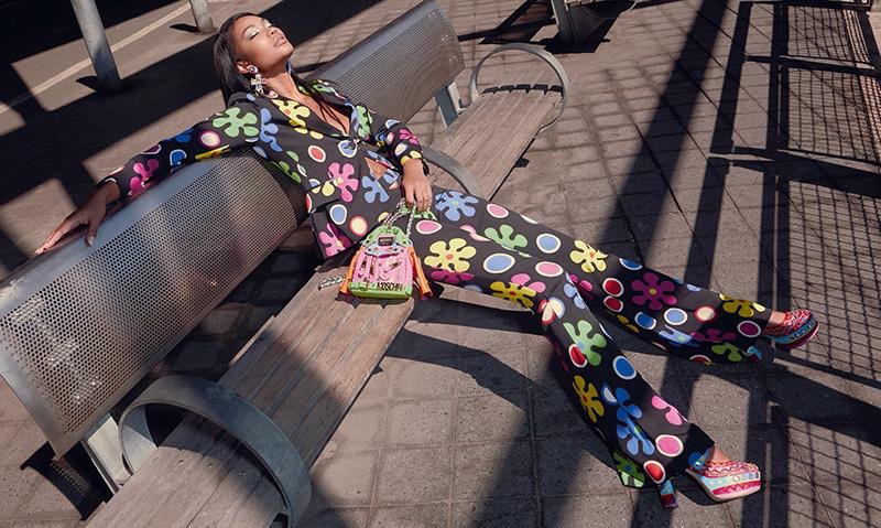 Sitting on a bench, Chanel Iman poses in quirky pantsuit from Moschino