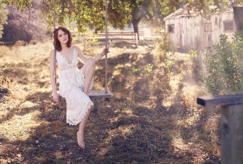 Posing on a swing, Emma Stone wears white crochet lace dress