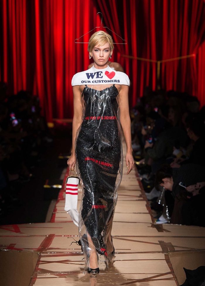 Stella Maxwell wears black dress covered with laundromat bag and hanger from Moschino’s fall-winter 2017 collection