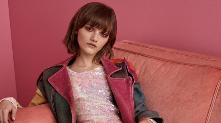 Lounging on a couch, Peyton Knight models vintage leather jacket and Christopher Kane sequined dress