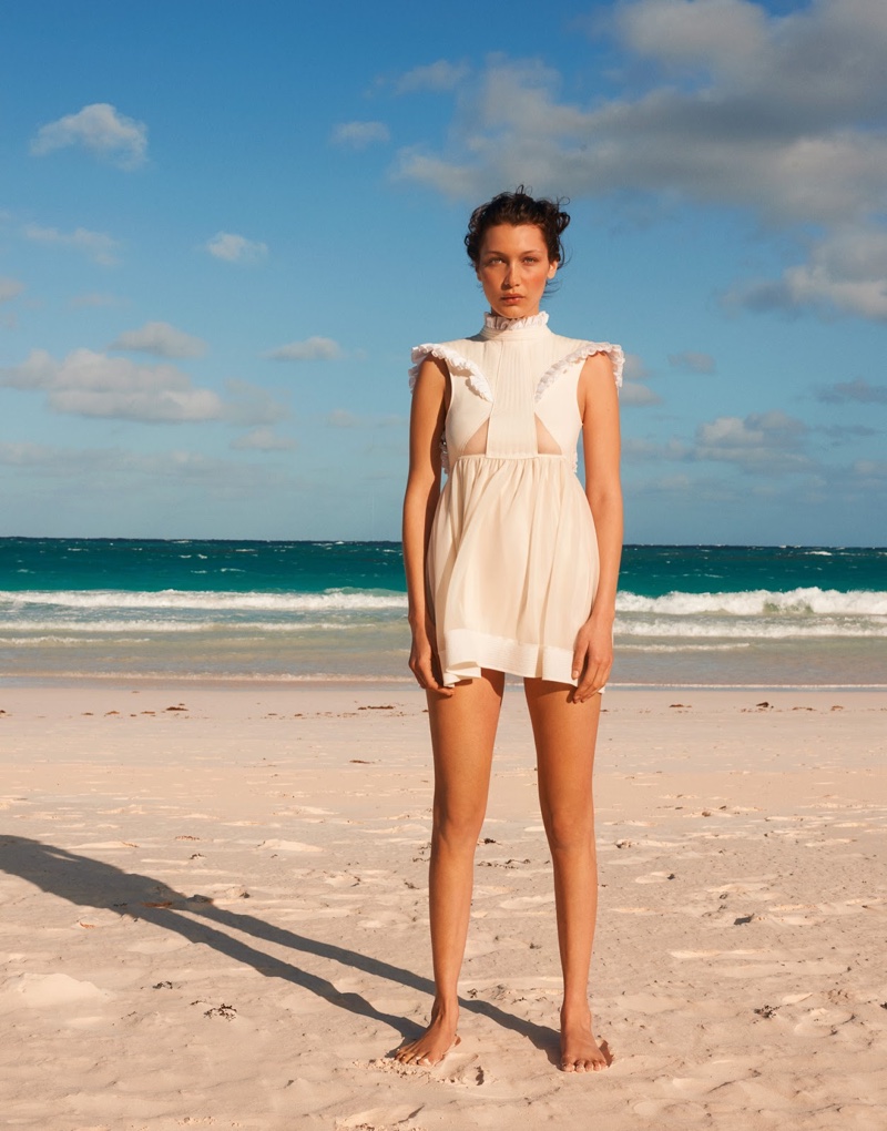 On the beach, Bella Hadid models a little white dress