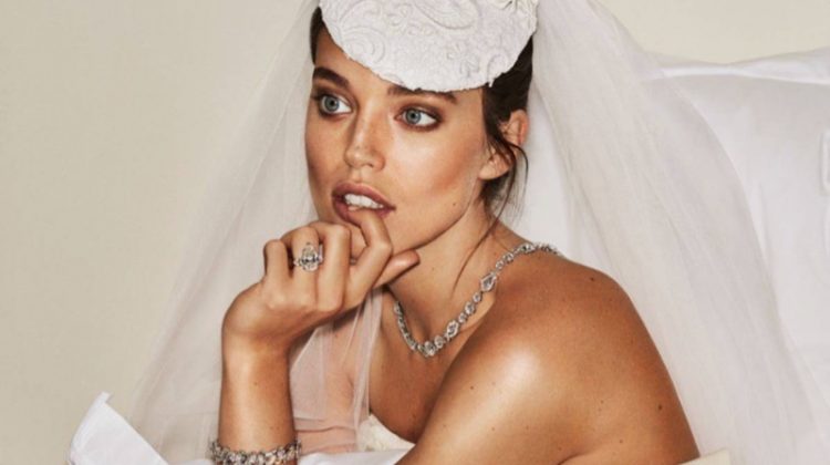 Sitting on a bed, Emily DiDonato wears Graff jewelry with Oscar de la Renta Bridal wedding dress