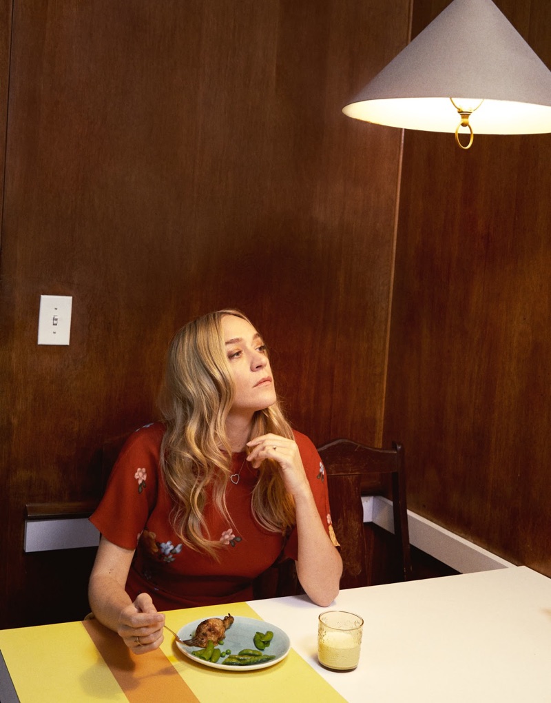 Chloe Sevigny poses at a table wearing a Magda Butrym dress