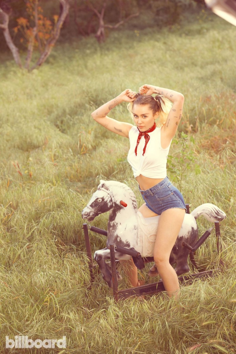 Looking cowgirl chic, Miley Cyrus poses in white t-shirt and denim shorts