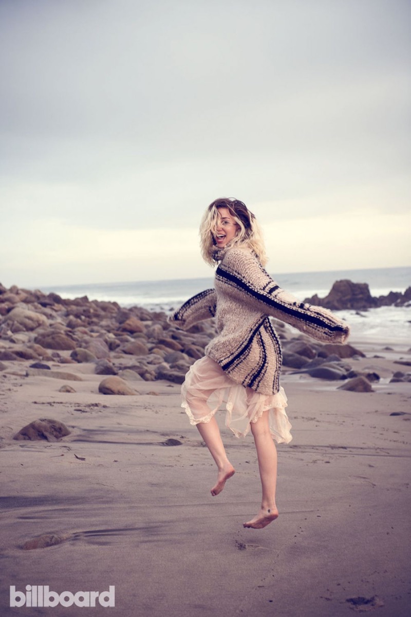 Posing on the beach, Miley Cyrus wears knit sweater over sheer skirt