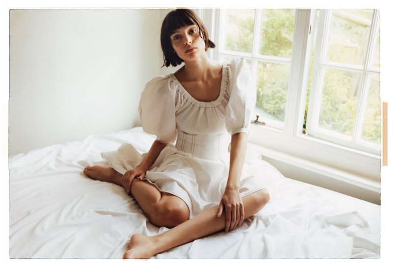 Posing in bed, Charlee Fraser wears Rejina Pyo dress