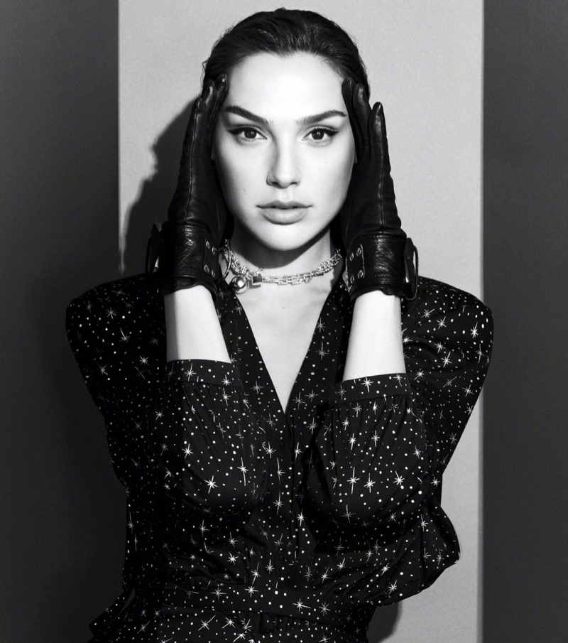 Photographed in black and white, Gal Gadot wears leather gloves and star print dress