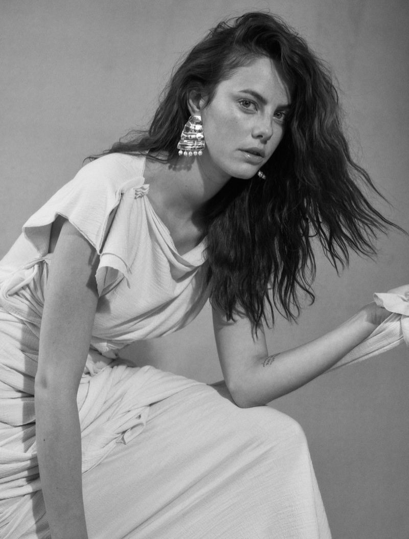 Photographed in black and white, Kaya Scodelario wears Loewe dress and earrings