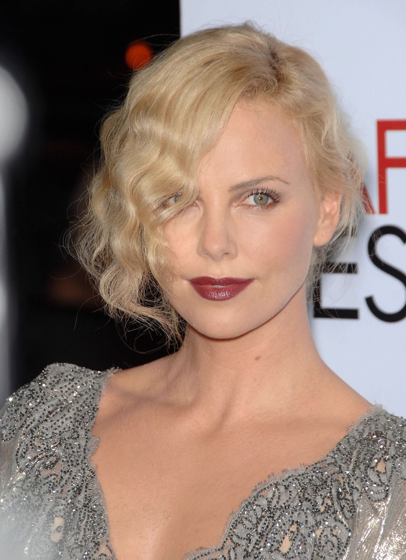 Actress Charlize Theron wears her hair in tousled finger waves in a modern, 1920s inspired updo.