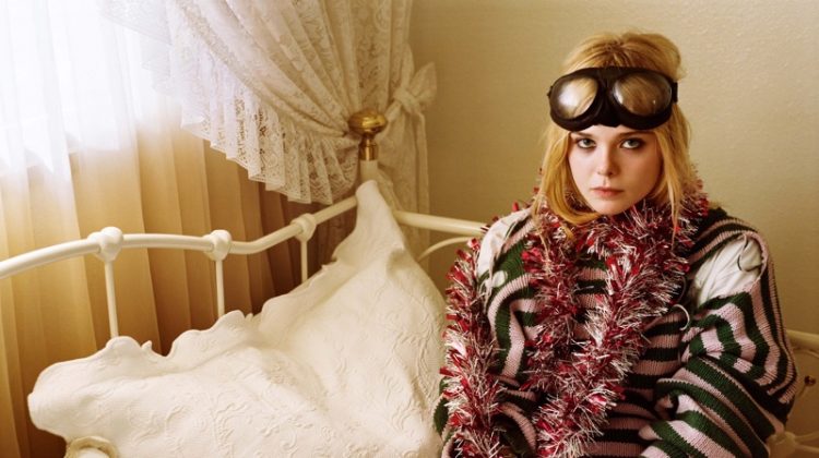 Posing in bed, Elle Fanning wears a whimsical look with a striped sweater