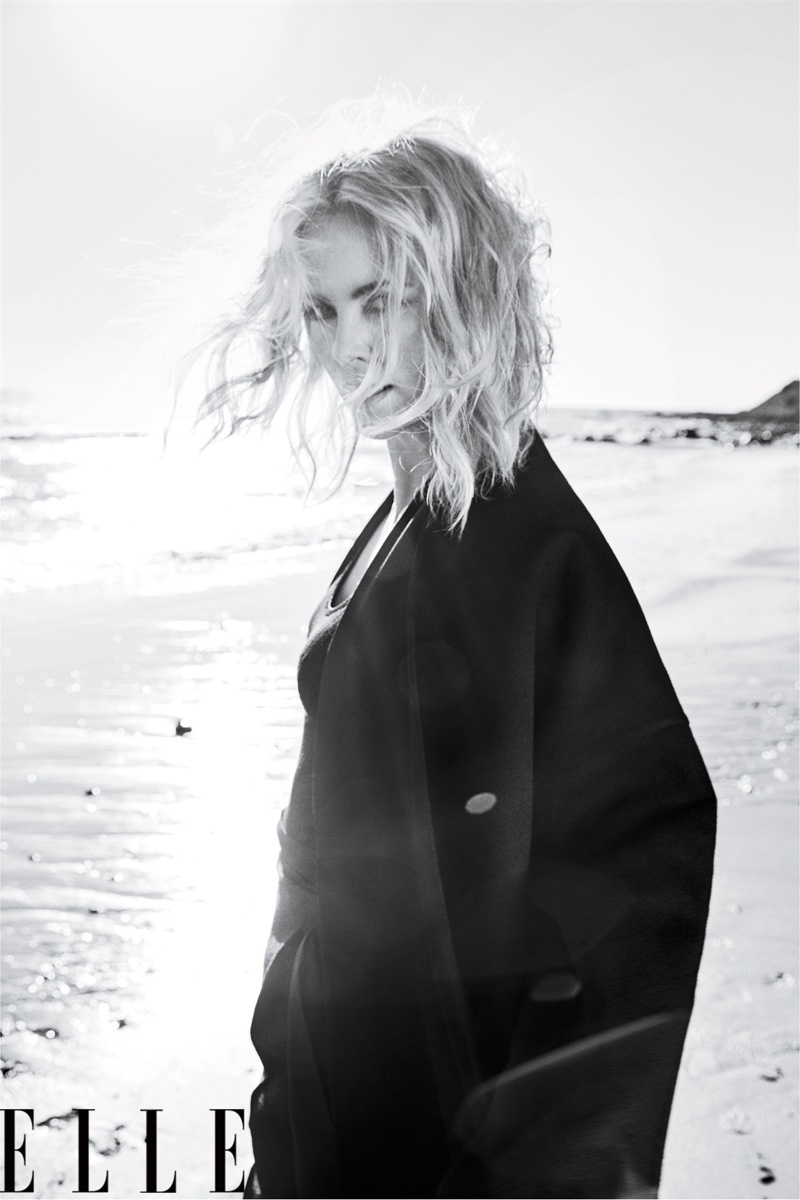 Photographed in black and white, Charlize Theron wears Valentino Haute Couture coat and pants