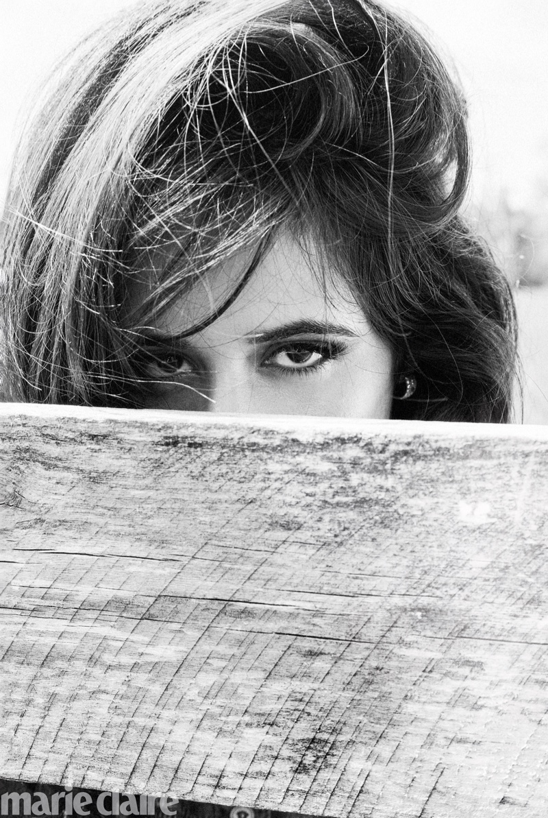 Photographed in black and white, Camila Cabello wears Versace top and De Beers earrings