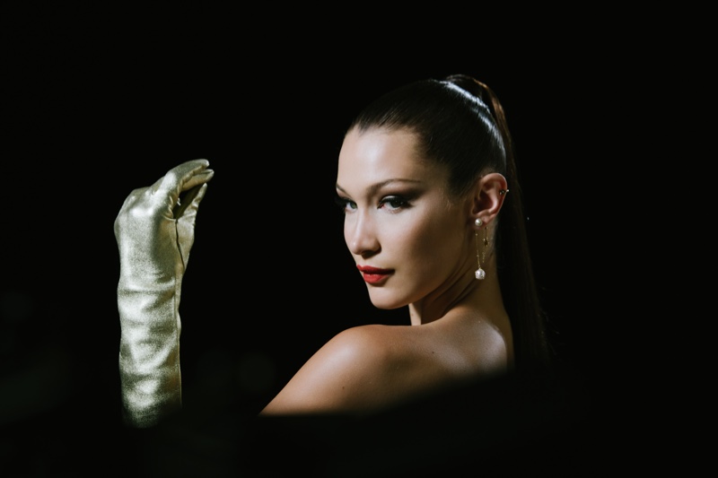 Wearing gloves, Bella Hadid appears on set of Dior makeup shoot