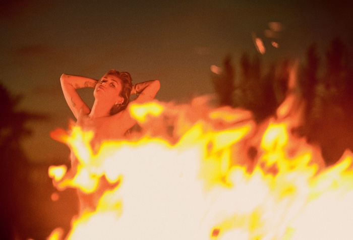 Through the fire, Miley Cyrus goes topless