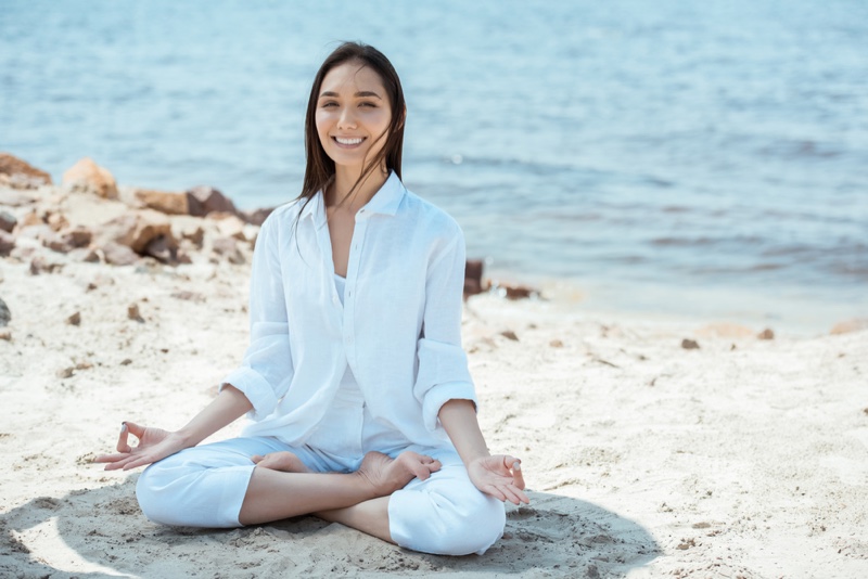 Woman in Yoga Pose Wearing White Outfit at Beach