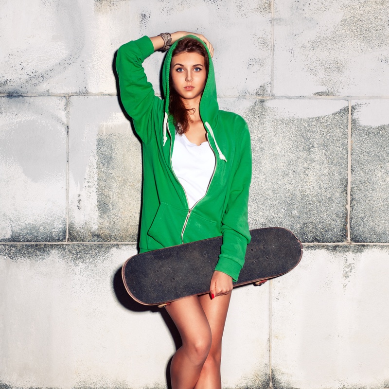 Woman in Green Hoodie with Skateboard