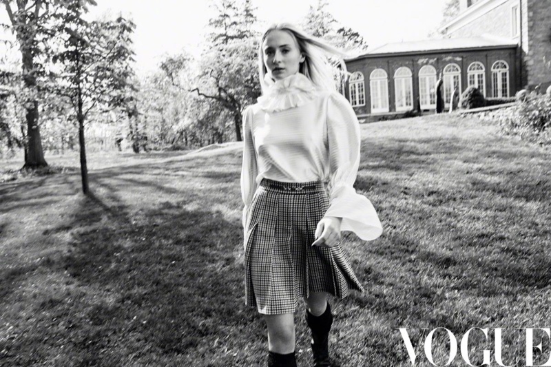 Sophie Turner poses in elegant blouse with plaid skirt