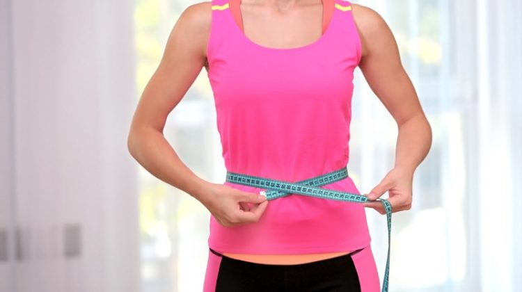 Benefits of Starting the Keto Diet Woman Measuring Waist Pink Top Workout Clothes