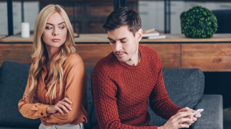 Is Your Partner Cheating? Young Couple Suspicious Woman Man Phone Couch