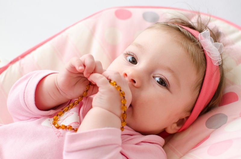 Baby Holding Amber Teething Necklace