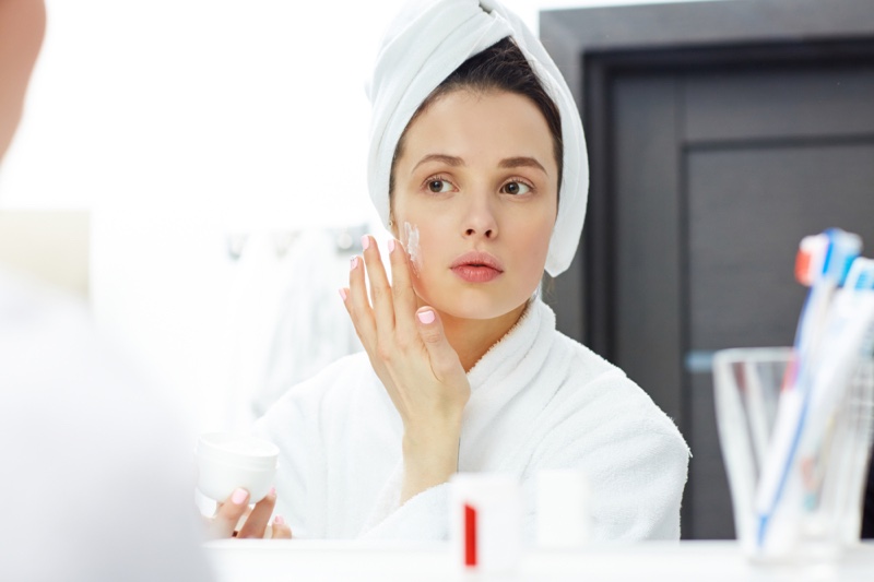 Woman Applying Moisturizer Towel Mirror