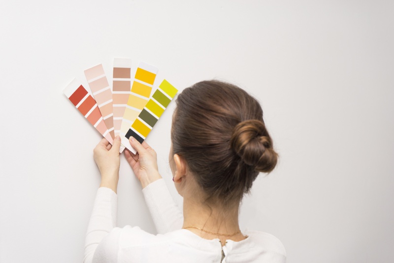 Woman Holding Paint Swatches Wall