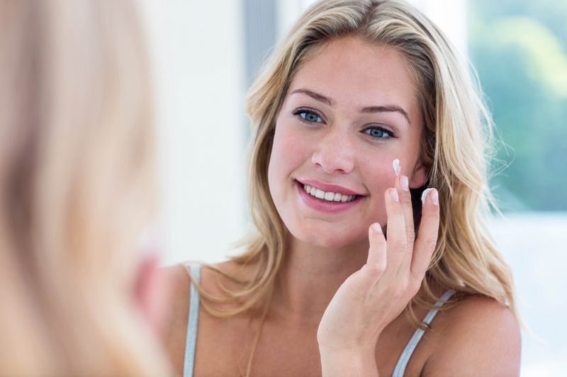 Blonde Woman Moisturizing Face Smiling