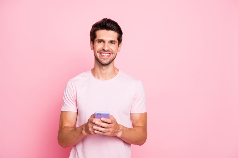 Smiling Man Pink T-Shirt Holding Phone