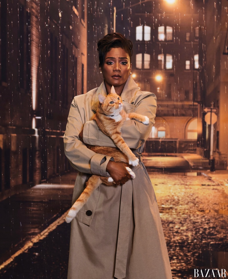 Posing with a cat, Tiffany Haddish wears Hermès trench coat with Tiffany & Co. earrings