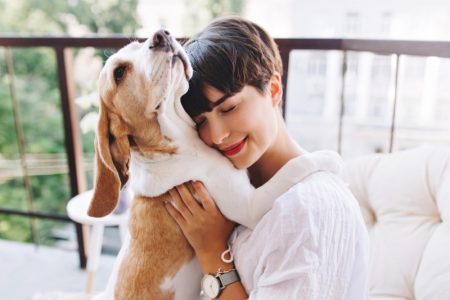 Can a Dog ACL Brace Help Relieve Your Dog’s Pain? Smiling Brunette Woman Holding Dog