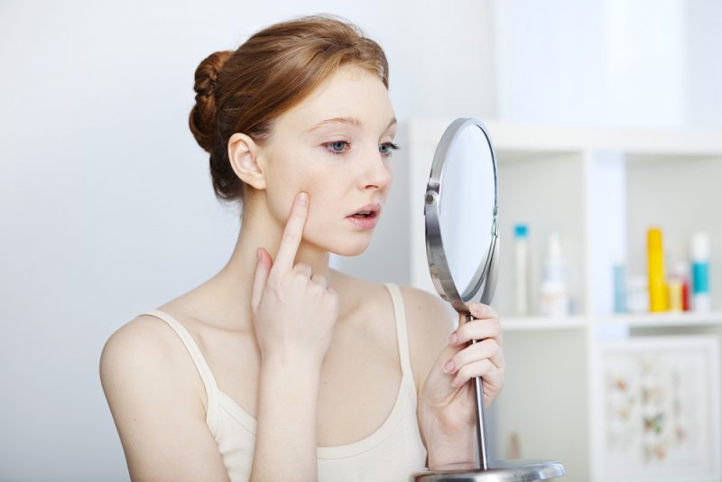 Woman Checking Face in Mirror