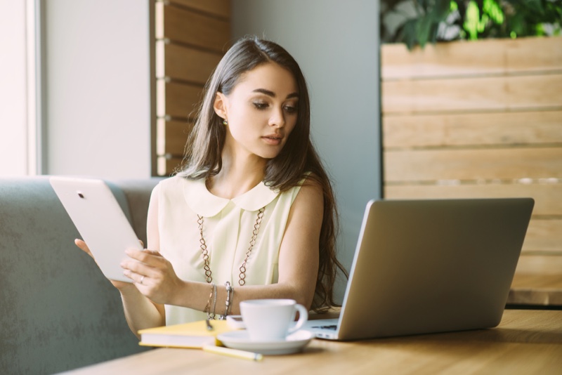 Attractive Woman Holding Tablet Looking Laptop