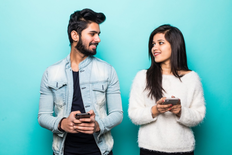 Indian Couple Looking Each Other Holding Phones